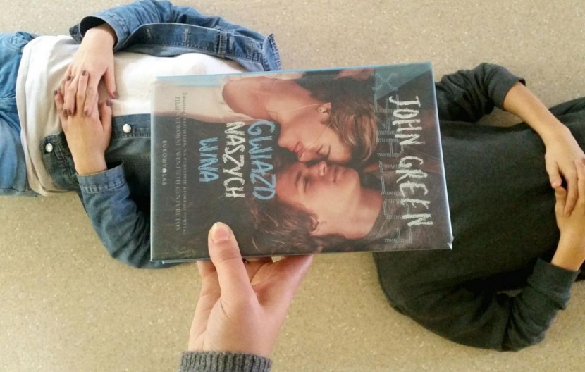 Zdjęcie przedstawia leżącą osobę oraz książkę. Zdjęcie prezentuje przykład zadania konkursowego.